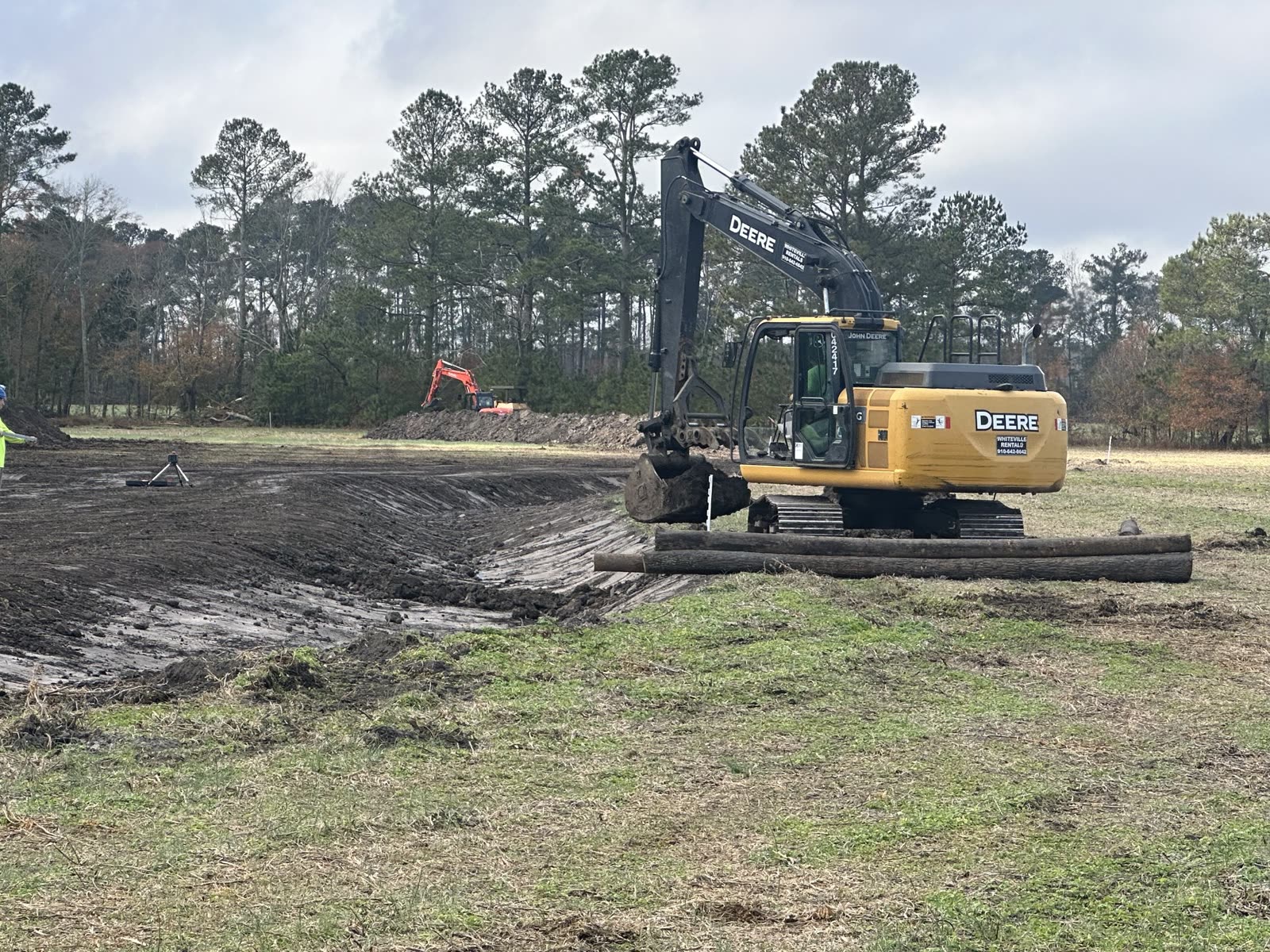 John Deere excavator shaping a new pond basin