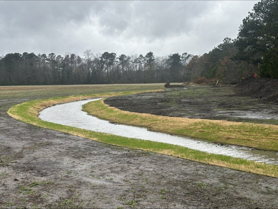Finished restored stream channel curving through a broad reclaimed field